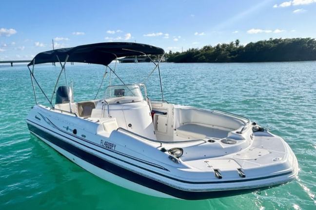 White boat with canopy floats on turquoise water under clear blue sky.