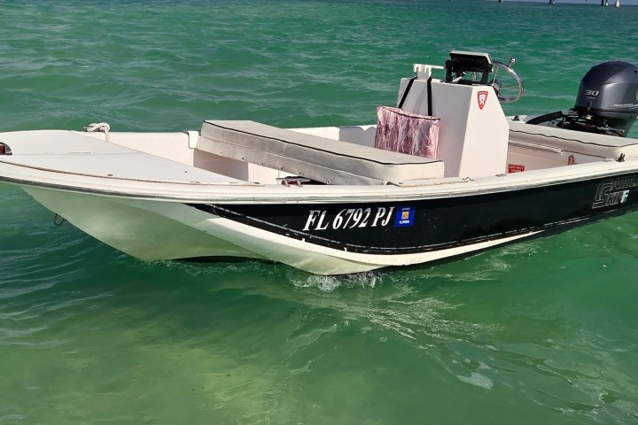 Small motorboat with white and black hull on green water.